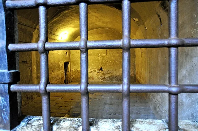 Una puerta de celda con barrotes de hierro en las cárceles del Palacio Ducal, con una sala abovedada de piedra detrás
